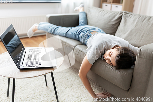 Image of bored woman with laptop lying on sofa at home