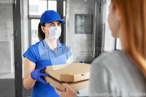 Image of delivery girl in mask giving pizza boxes to woman