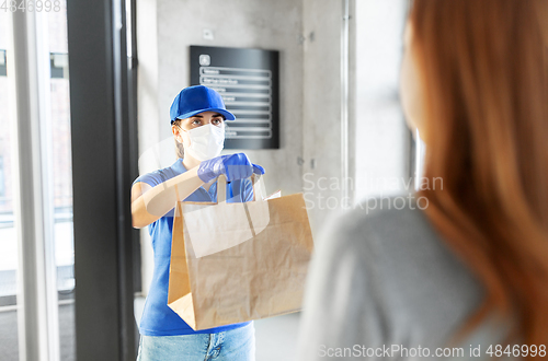 Image of delivery girl in mask giving paper bag to customer