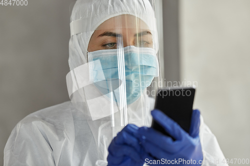 Image of doctor in protective wear with smartphone