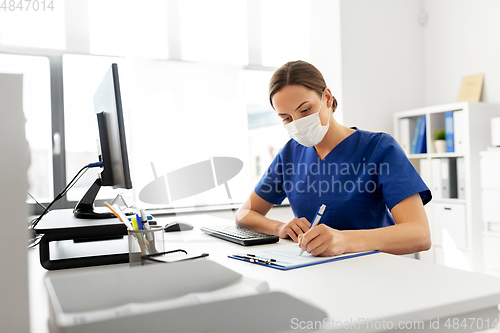 Image of doctor or nurse in mask with clipboard at hospital