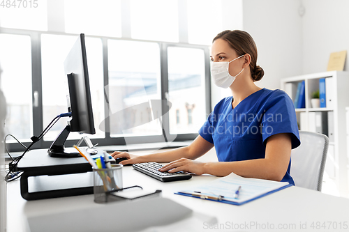 Image of doctor or nurse in mask with computer at hospital