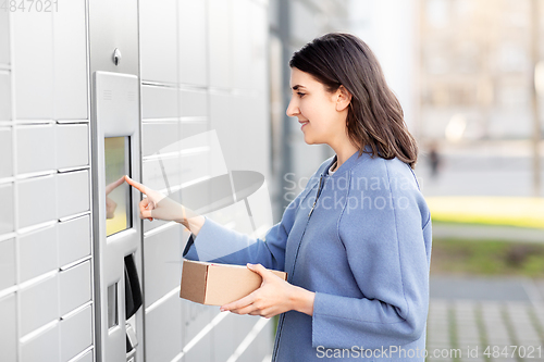 Image of smiling woman with box at automated parcel machine