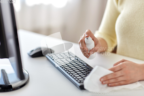 Image of close up of woman cleaning keyboard with sanitizer