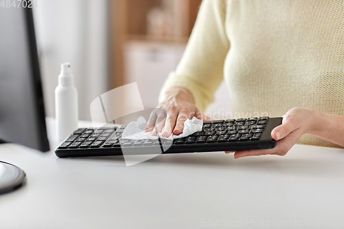 Image of close up of woman cleaning keyboard with tissue