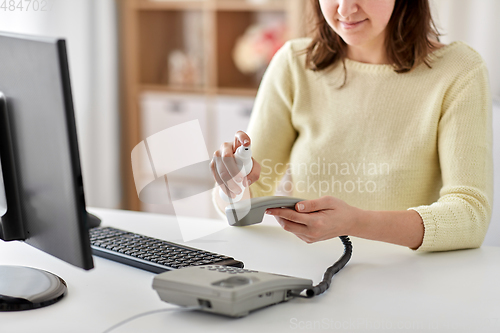 Image of close up of woman cleaning phone with sanitizer