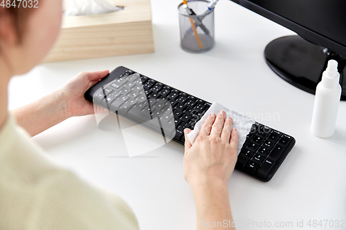 Image of close up of woman cleaning keyboard with tissue