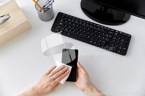 Image of close up of hands cleaning smartphone with tissue