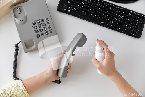 Image of close up of woman cleaning phone with sanitizer