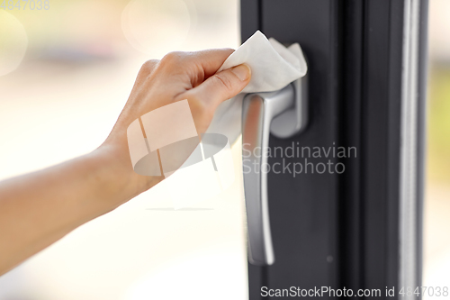 Image of woman cleaning window handle with wet wipe