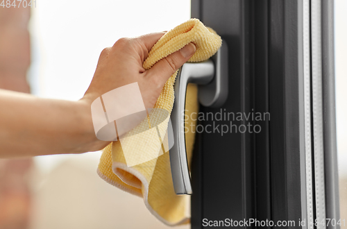 Image of hand cleaning window handle with microfiber rag