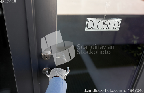 Image of hand in glove trying to open closed office door