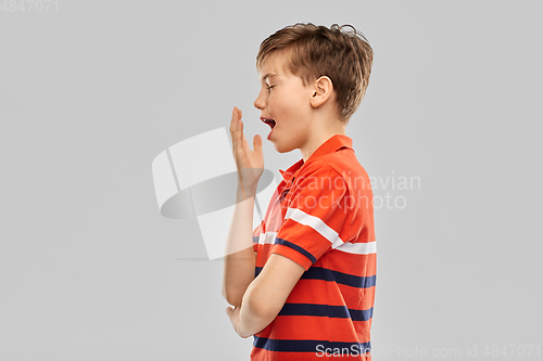 Image of portrait of tired yawning boy in red polo t-shirt
