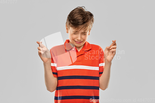 Image of boy in red polo t-shirt holding fingers crossed