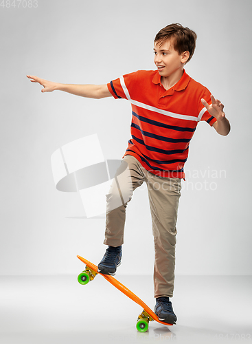 Image of smiling boy riding on short skateboard