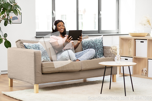 Image of woman with tablet pc listening to music at home