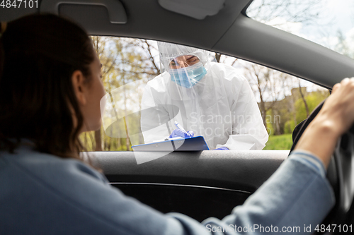 Image of healthcare worker with clipboard and woman in car