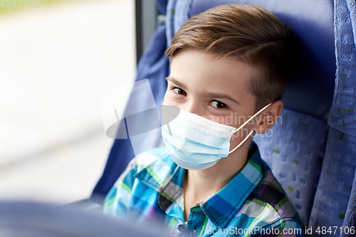Image of boy in mask sitting in travel bus or train