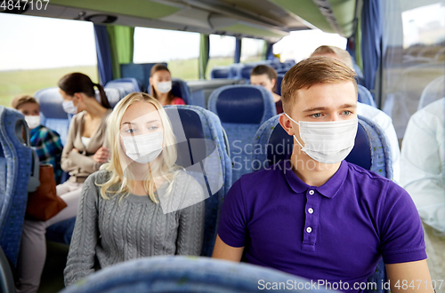 Image of couple or passengers in masks in travel bus