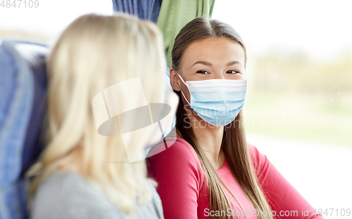 Image of young women in masks sitting in travel bus