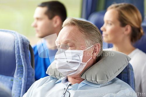 Image of senior man in mask sleeping in travel bus