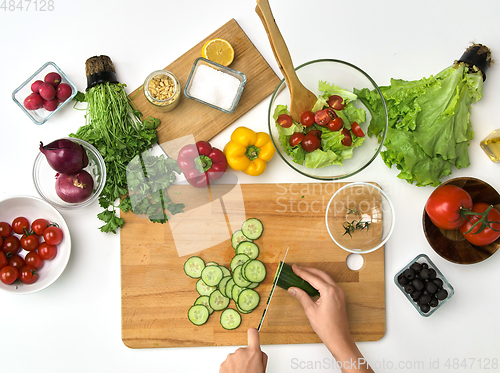 Image of hands chopping cucumber on cutting board