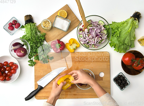 Image of hands preparing pepper for salad at kitchen