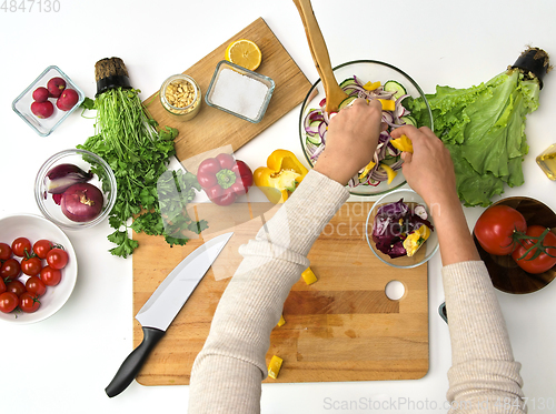 Image of hands cooking vegetable salad on kitchen table