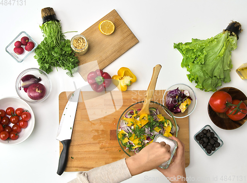 Image of hands cooking vegetable salad on kitchen table