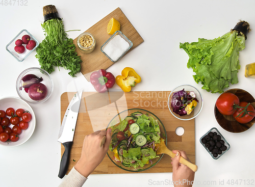 Image of hands cooking vegetable salad on kitchen table
