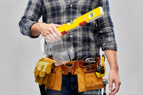 Image of male builder with level and working tools on belt