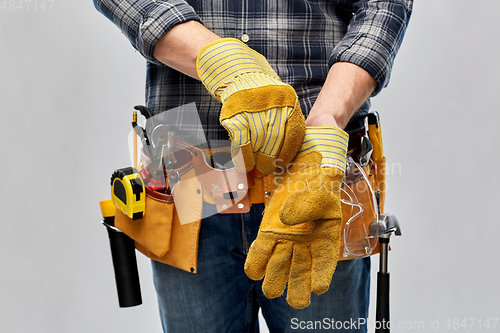 Image of builder with working tools putting gloves on