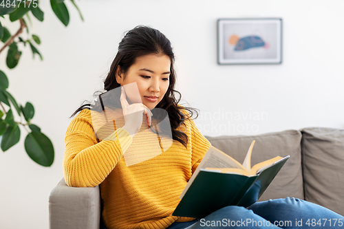 Image of asian young woman reading book at home
