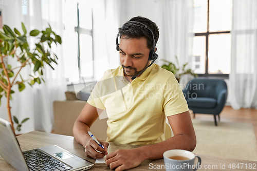 Image of indian man with headset and laptop working at home