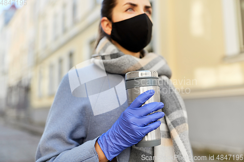 Image of woman in reusable mask with tumbler in city