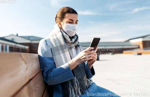 Image of woman in face mask with smartphone in city