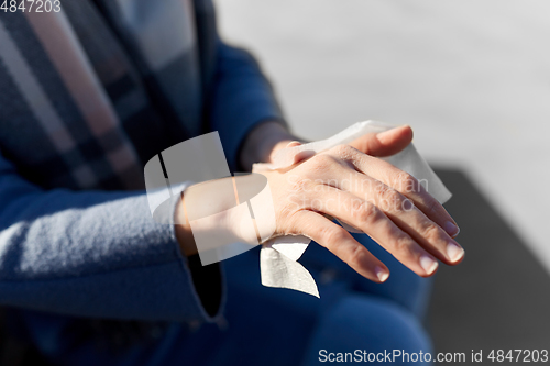 Image of close up of woman cleaning hands with wet wipe