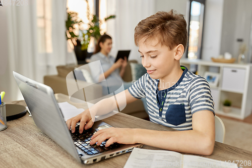 Image of student boy with laptop learning at home