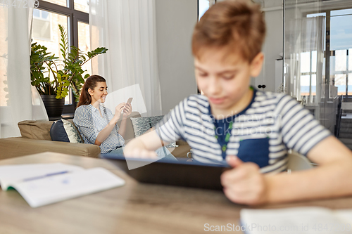 Image of mother with smartphone and son learning at home