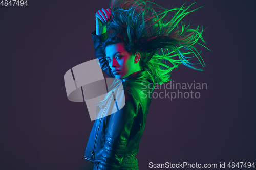 Image of Beautiful woman\'s portrait with blowing hair on dark studio background in colorful neon light