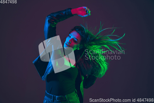 Image of Beautiful woman\'s portrait with blowing hair on dark studio background in colorful neon light
