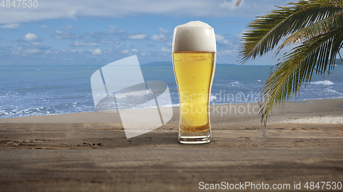 Image of Glass with cold beer with sea or ocean beach on background