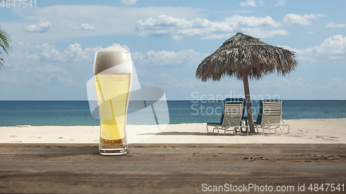 Image of Glass with cold beer with sea or ocean beach on background