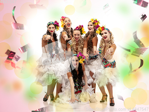 Image of Beautiful young women in carnival costumes in colorful neon lights on white background in flying confetti