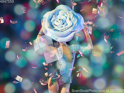 Image of Young female dancer with huge floral hat in neon light on gradient background in flying confetti