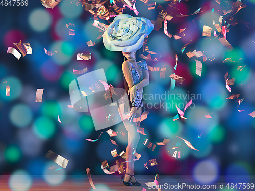 Image of Young female dancer with huge floral hat in neon light on gradient background in flying confetti