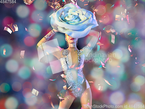 Image of Young female dancer with huge floral hat in neon light on gradient background in flying confetti