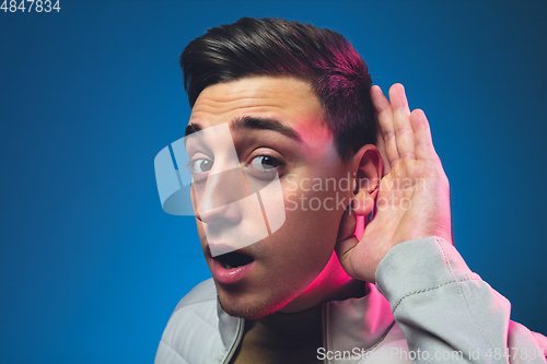 Image of Caucasian man\'s portrait isolated on blue studio background in neon light