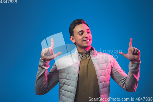 Image of Caucasian man\'s portrait isolated on blue studio background in neon light
