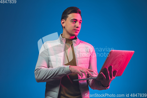 Image of Caucasian man\'s portrait isolated on blue studio background in neon light